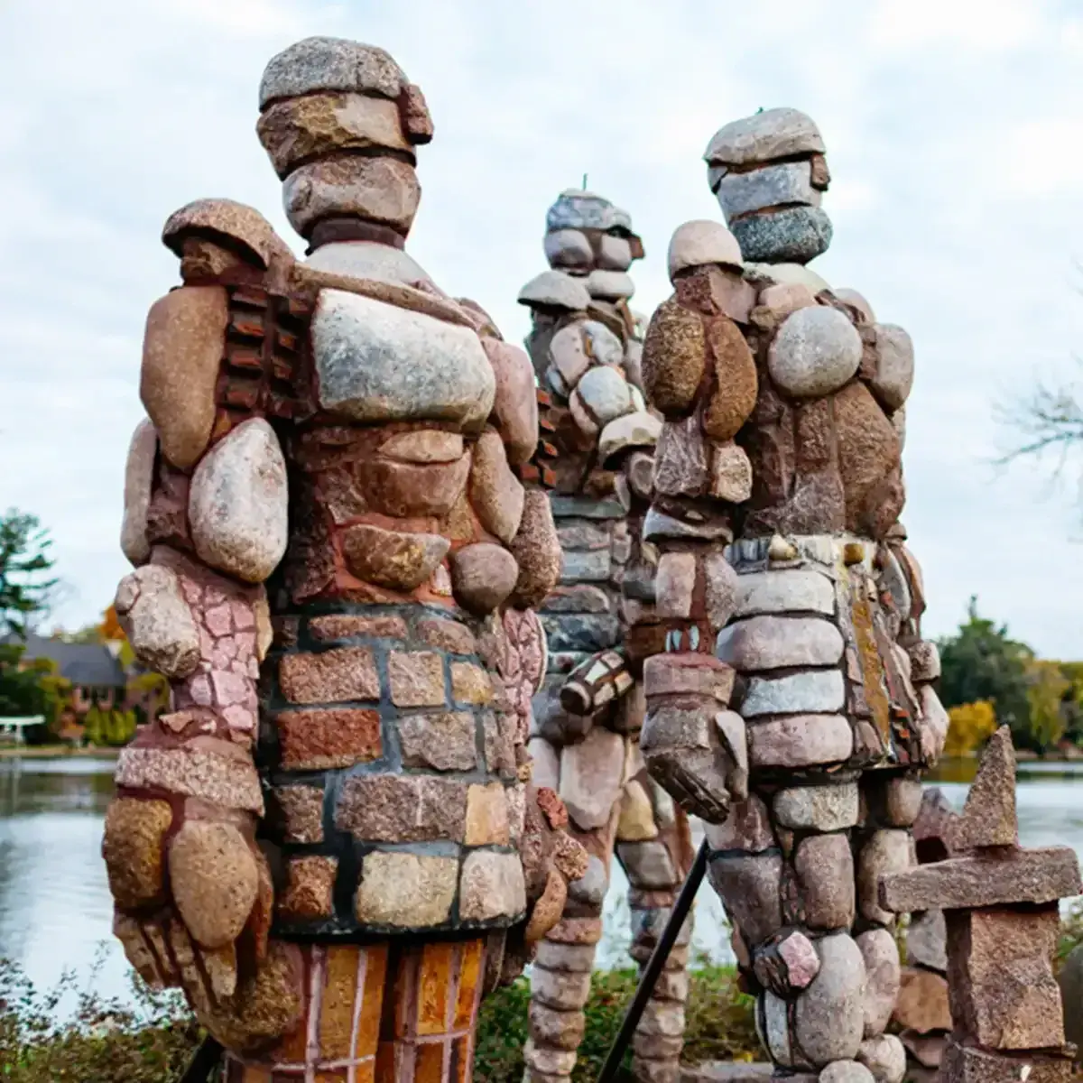 Stacked stone sculptures in a snowy outdoor park against a cloudy sky